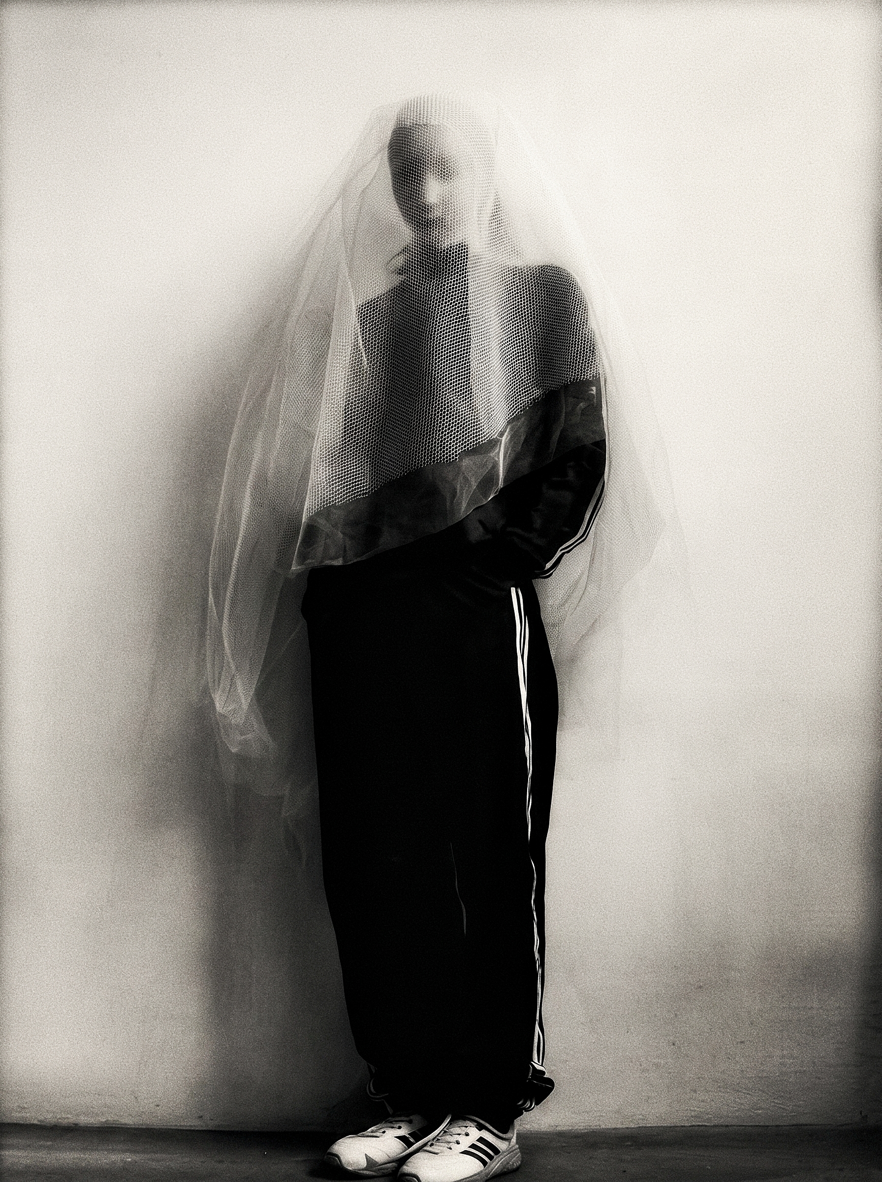 Negative Space — a standing figure in dark sportswear beneath a translucent mesh veil.